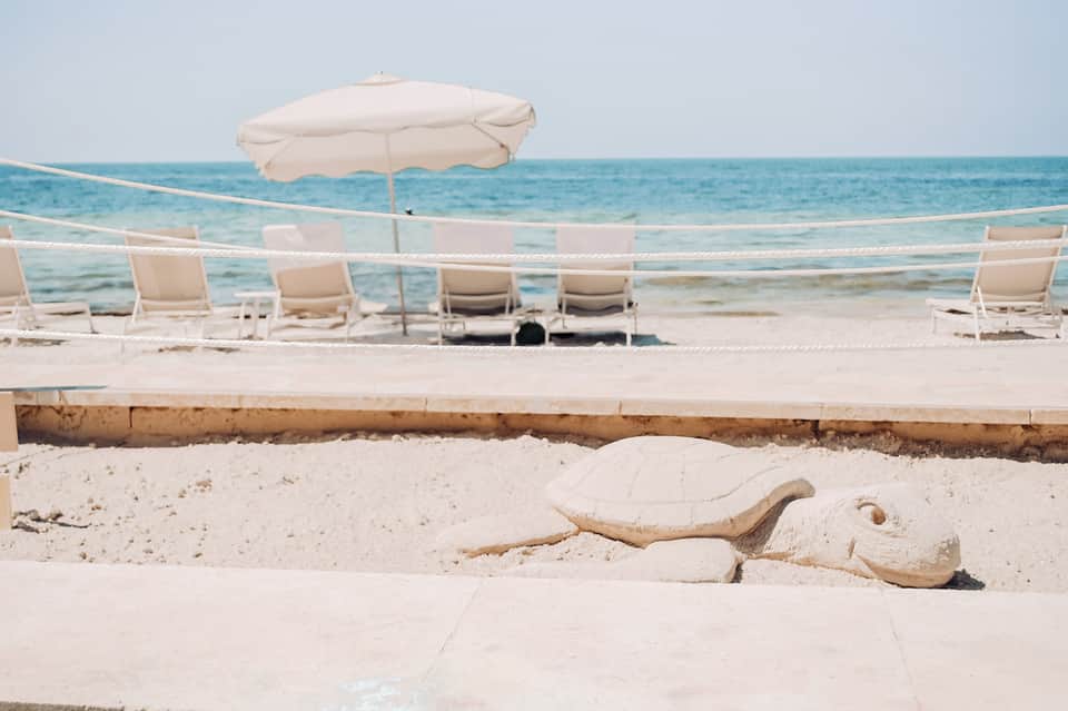 Beach lounge area with white umbrellas, chairs, and turquoise ocean view