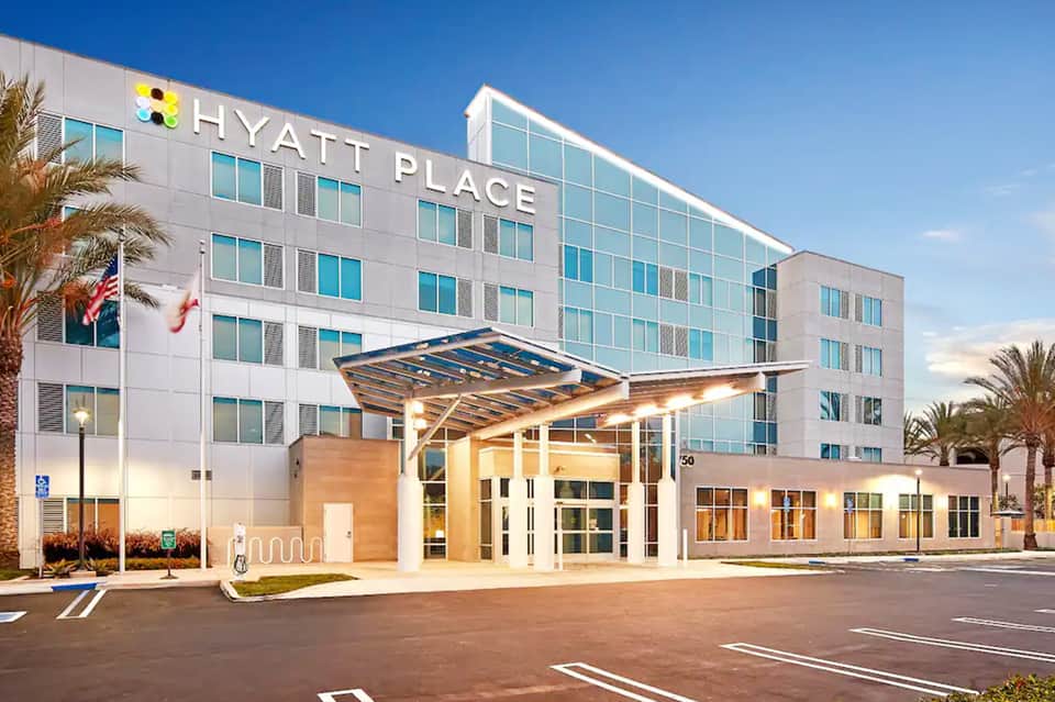 Hyatt Place hotel exterior at dusk with illuminated entrance, palm trees, and contemporary architecture
