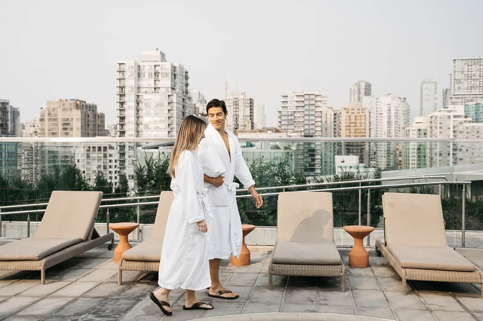 Couple in white robes on rooftop terrace overlooking city skyline