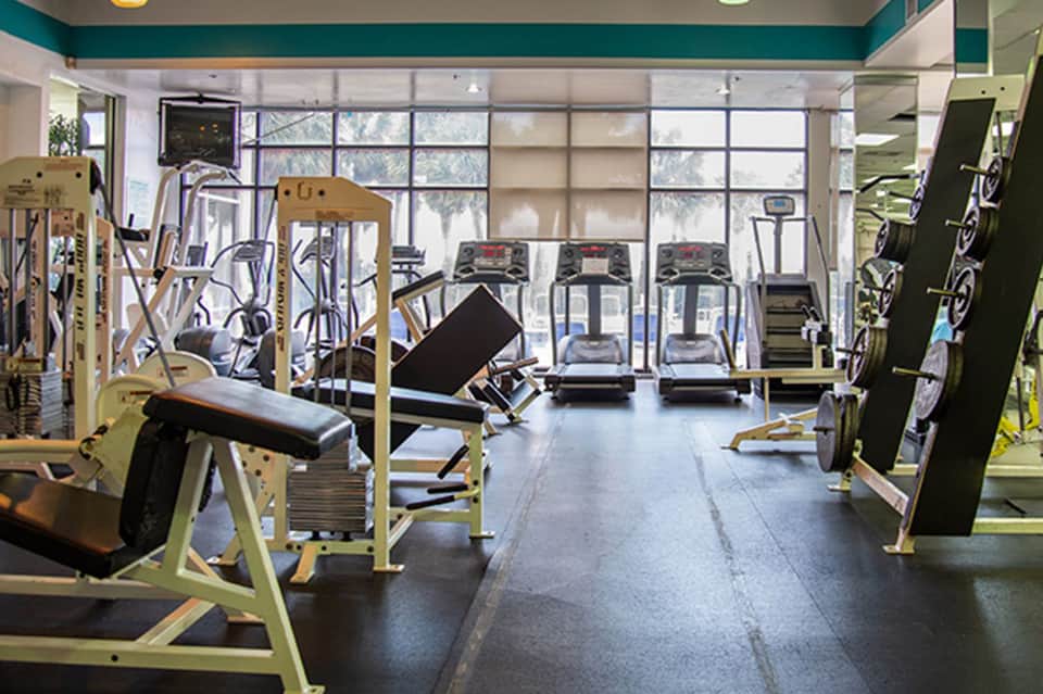 Hotel fitness center with cardio machines, free weights, treadmills, and large windows