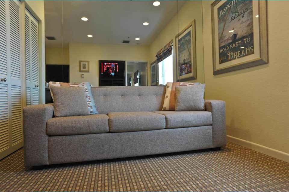 Yellow-walled media room with gray upholstered sofa, recessed lighting, and inspirational wall art