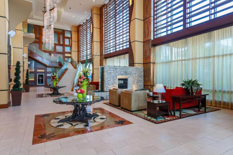 Modern hotel lobby with high ceilings, wood beams, decorative plants, and seating areas