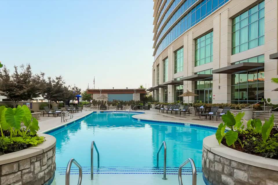 Resort outdoor swimming pool with lounge chairs, modern building facade, and landscaped gardens