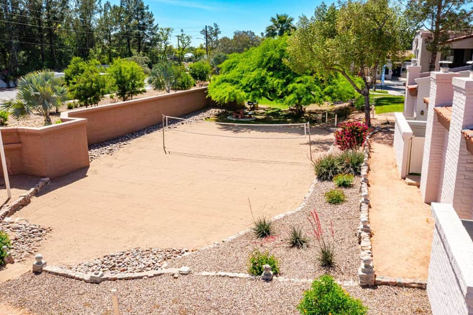 Desert landscaping with sand volleyball court, brick walls, and drought-resistant plants