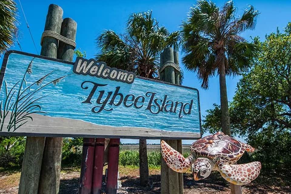 Welcome to Tybee Island sign with sea turtle sculpture and palm trees
