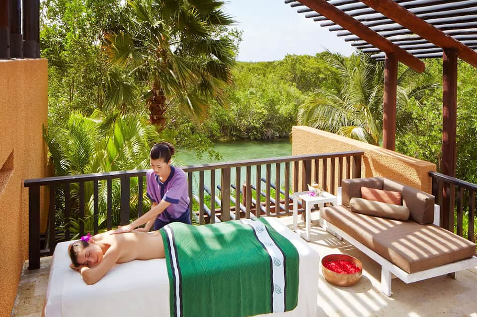 Outdoor spa treatment by the water with massage therapist and tropical jungle surroundings
