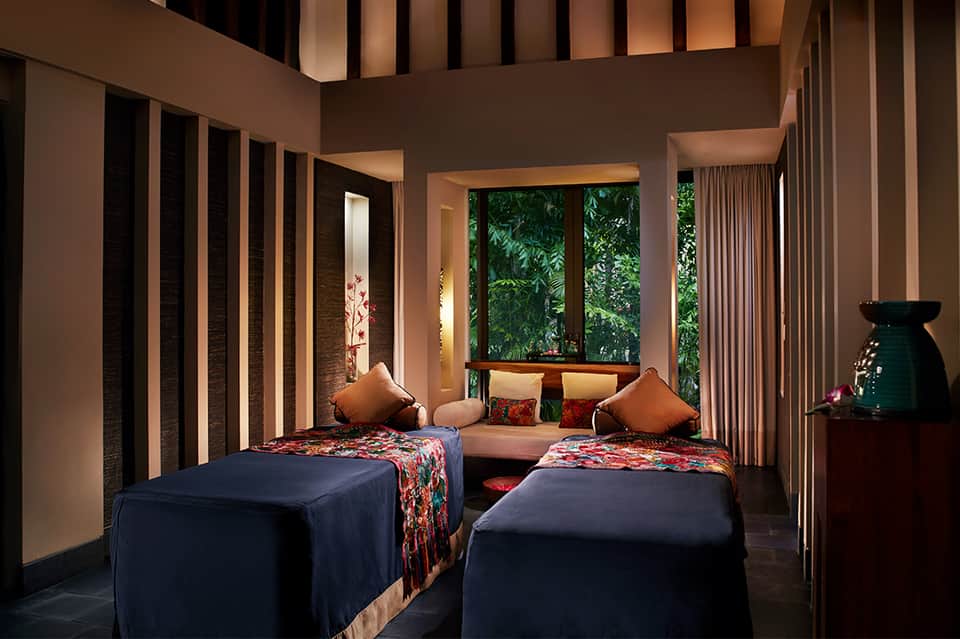 Spa treatment room with twin massage beds and tropical garden views