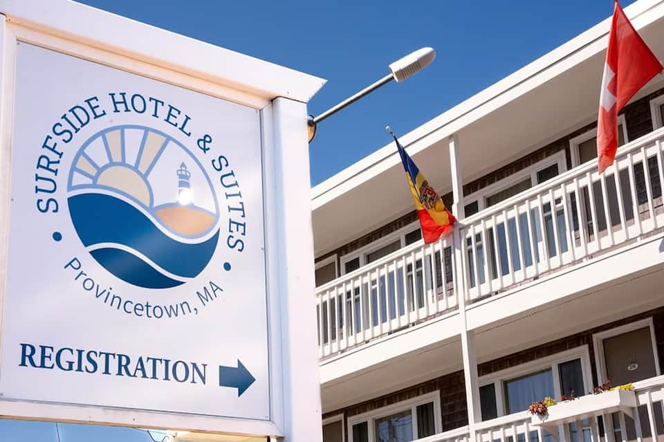 Surfside Hotel & Suites exterior sign in Provincetown, MA with multi-story building and flags