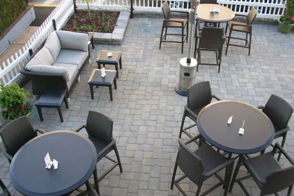 Overhead view of patio with round dining tables, bar seating, and lounge area on pavers