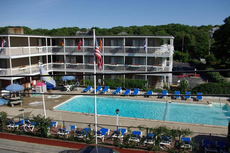 Outdoor pool with blue lounge chairs, multi-story beachfront hotel building, and palm trees