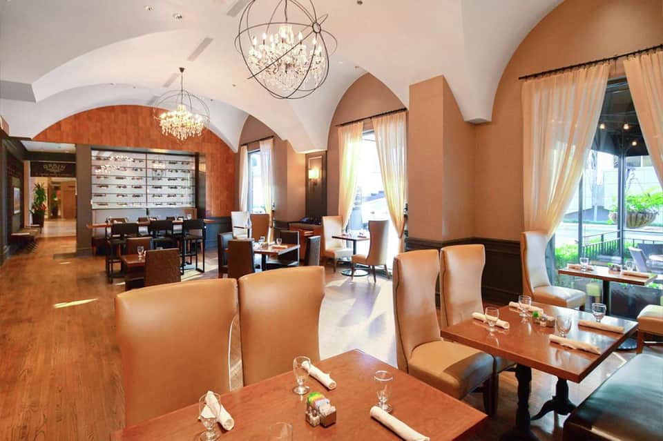 Elegant restaurant dining room with arched ceilings, warm lighting, and ocean views