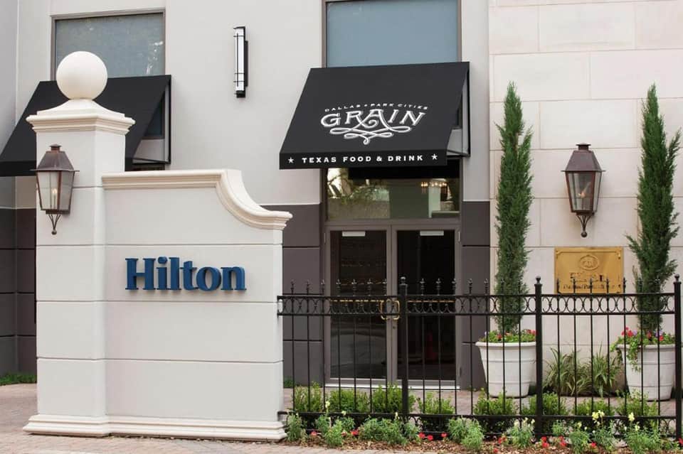Hilton hotel entrance with black awning for Grain restaurant and white stone facade