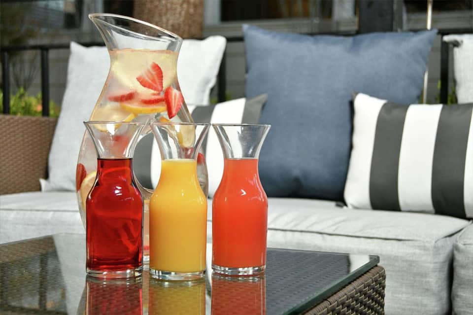 Outdoor patio table with fresh fruit beverages and striped cushioned seating in background