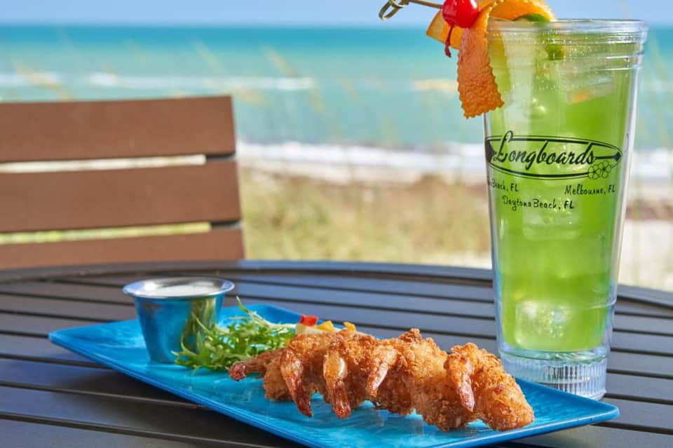 Fried shrimp platter with green cocktail and ocean view from beachfront dining table