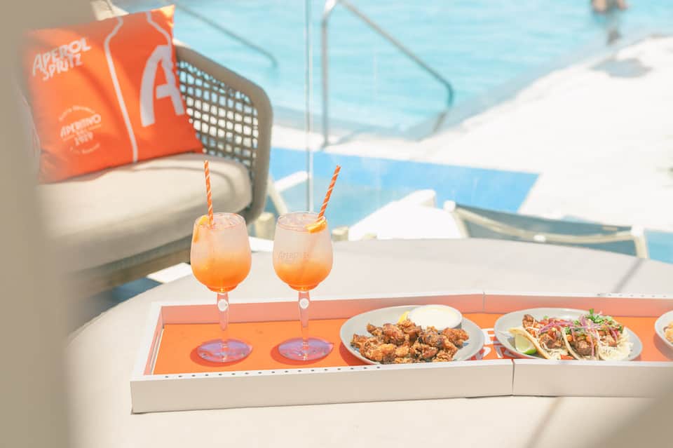Poolside dining with tropical cocktails and appetizers overlooking blue water