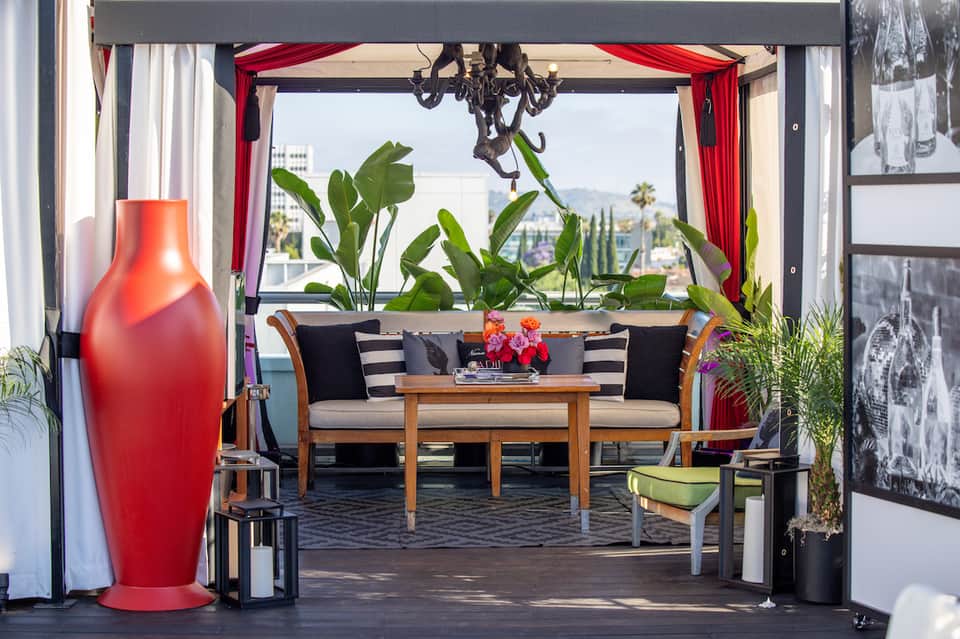 Modern resort lounge with red vase, striped seating, red curtains, and city view