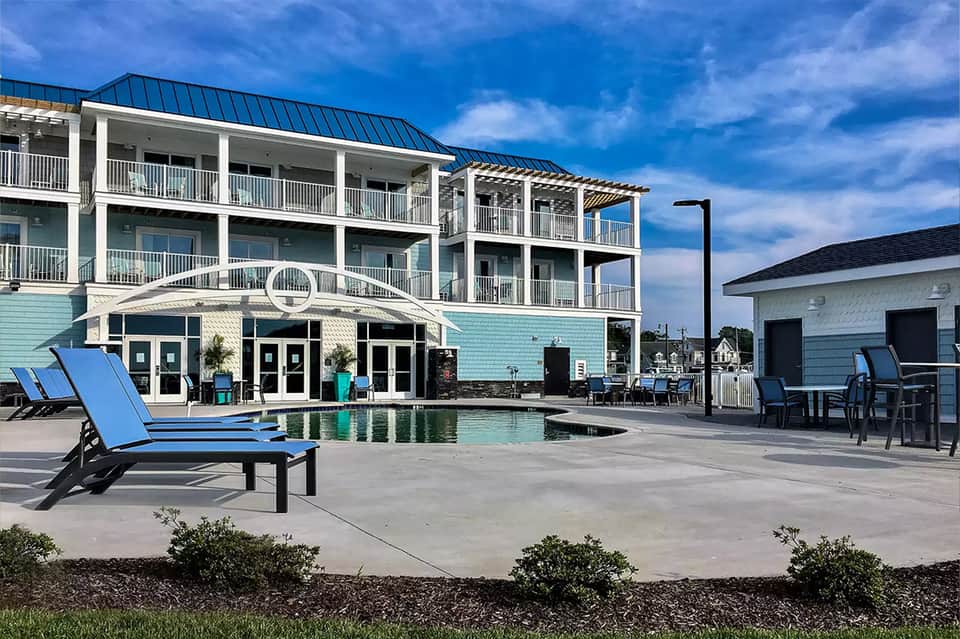 Waterfront resort with turquoise pool, modern architecture, wooden loungers, and gazebo