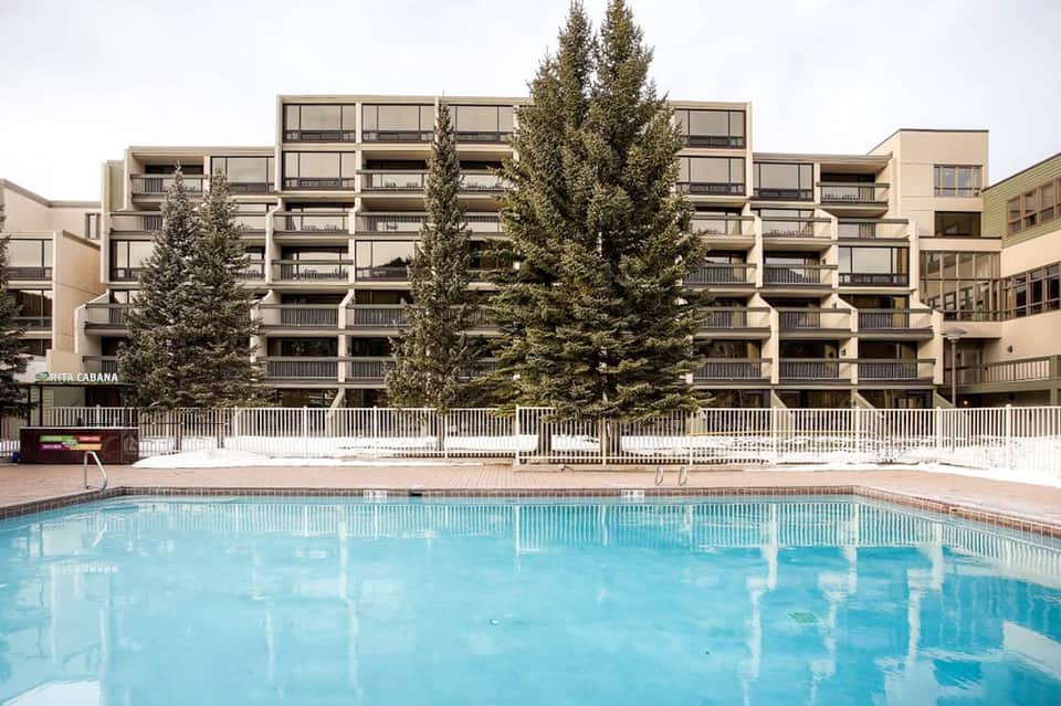 Modern residential building with evergreen trees reflected in swimming pool