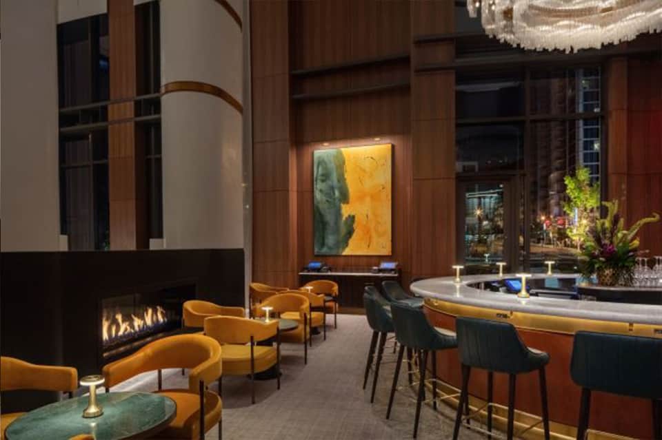 Luxury lounge with mustard chairs, fireplace, modern art, and curved wood ceiling details