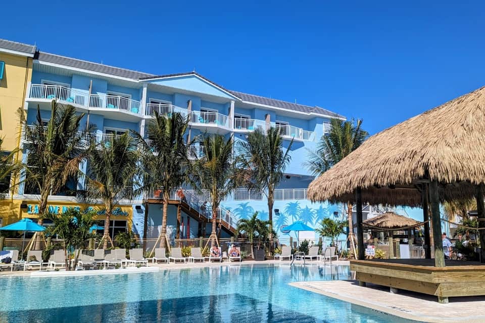 Resort pool area with thatched-roof cabana and beachfront building