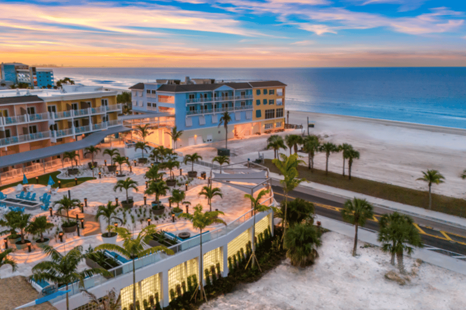Beachfront resort at sunset with colorful buildings, palm trees, and illuminated pathways