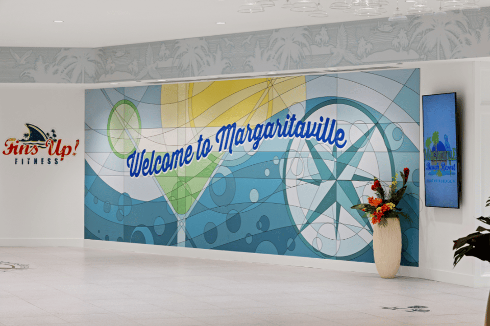 Hotel lobby entrance with 'Welcome to Margaritaville' sign and Fins Up Fitness branding