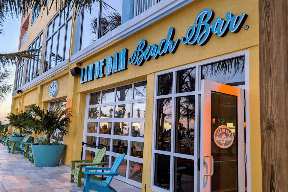 Tiki Beach Bar storefront with yellow exterior, blue signage, and colorful Adirondack chairs on patio