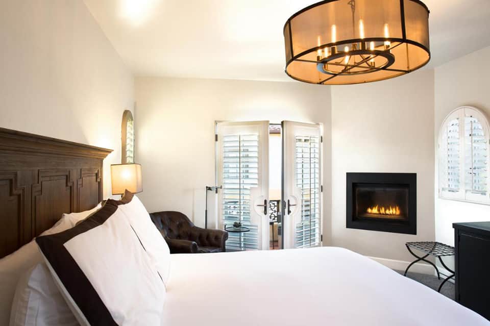 Luxurious hotel bedroom with fireplace, white bedding, and balcony doors