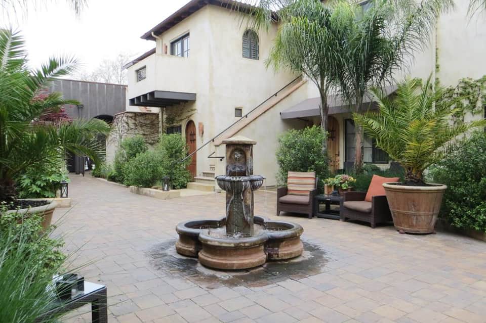 Spanish-style courtyard with central fountain, potted plants, and Mediterranean architecture