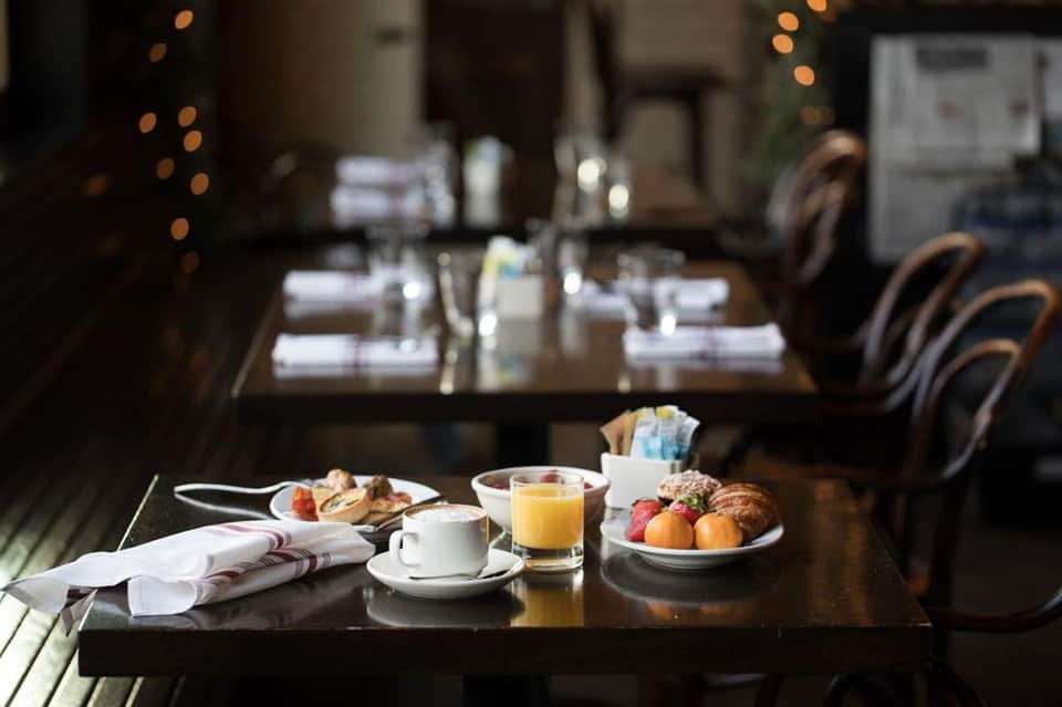 Elegant breakfast spread on dark table with coffee, pastries, juice, and fresh berries in dining room