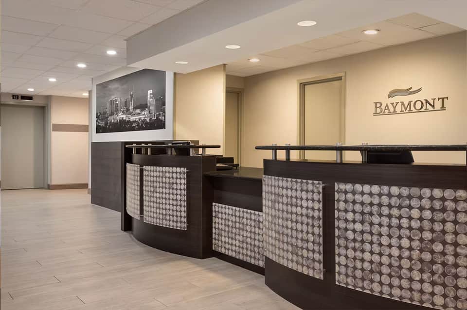 Hotel reception desk with geometric patterned panels and Baymont branding in neutral tones