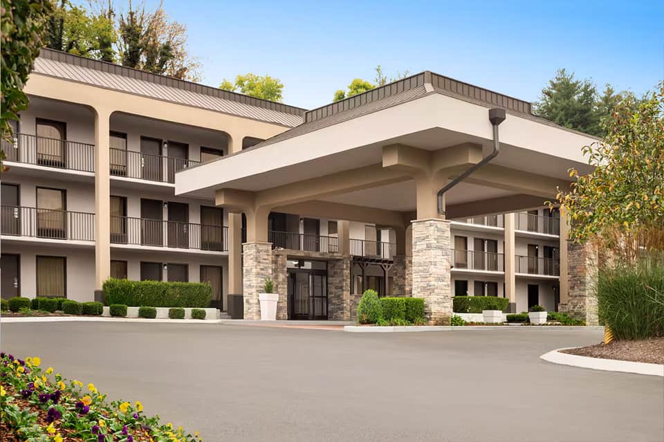 Contemporary hotel entrance with stone accents, multiple balconies, and landscaped driveway