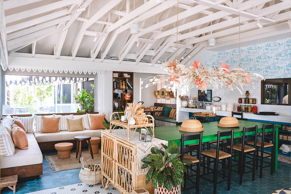 Bright coastal lounge with white exposed beams, wicker furniture, green bar counter, and ocean views