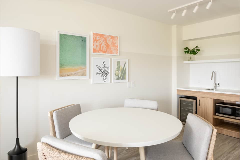 Modern dining area with white round table, gray chairs, and framed botanical artwork on walls