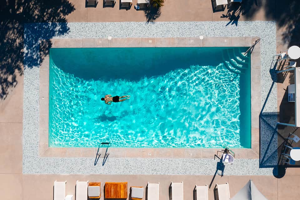 Aerial view of rectangular swimming pool with crystal clear turquoise water and lounge chairs on surrounding deck
