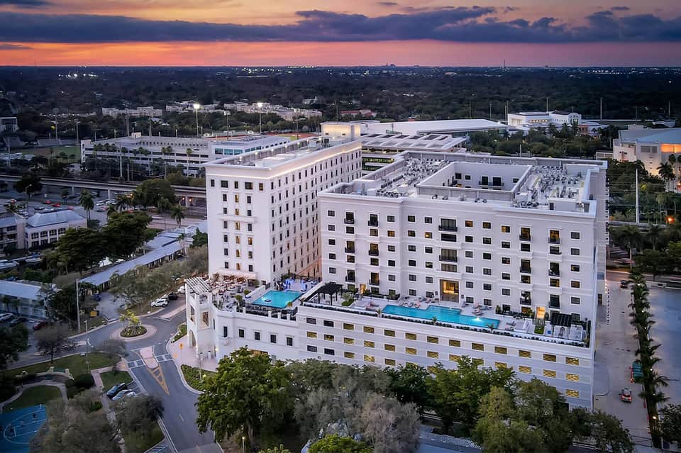 Contemporary white hotel building at dusk with pool and surrounding landscaping