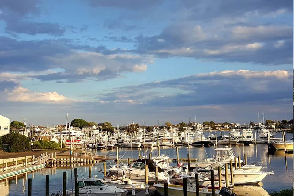 Marina at dusk with sailboats docked at wooden piers under a cloudy blue sky