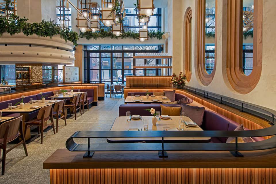 Modern restaurant interior with curved wooden details, purple booths, and contemporary oval wall art