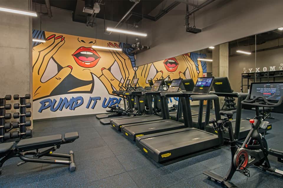 Fitness center with treadmills, exercise bikes, dumbbells, and motivational pop art wall mural