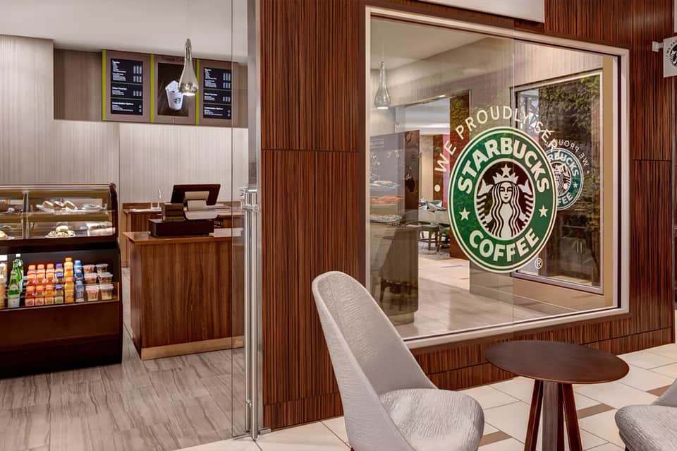 Modern Starbucks coffee shop interior with wood paneling, display cases, and seating area