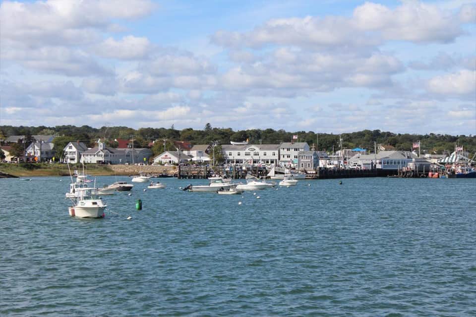 Coastal New England harbor town with moored boats and waterfront buildings