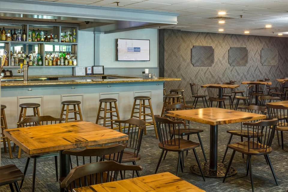 Casual dining area with wooden tables, bar seating, and herringbone patterned accent wall