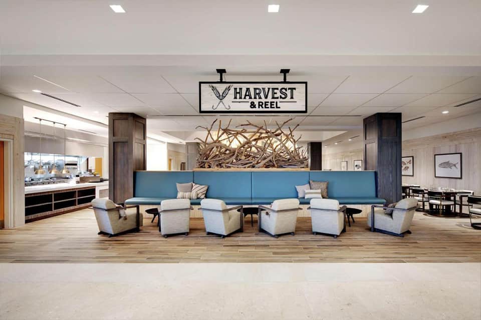 Harvest & Reel restaurant lobby with blue seating, wooden accent wall, and driftwood sculpture