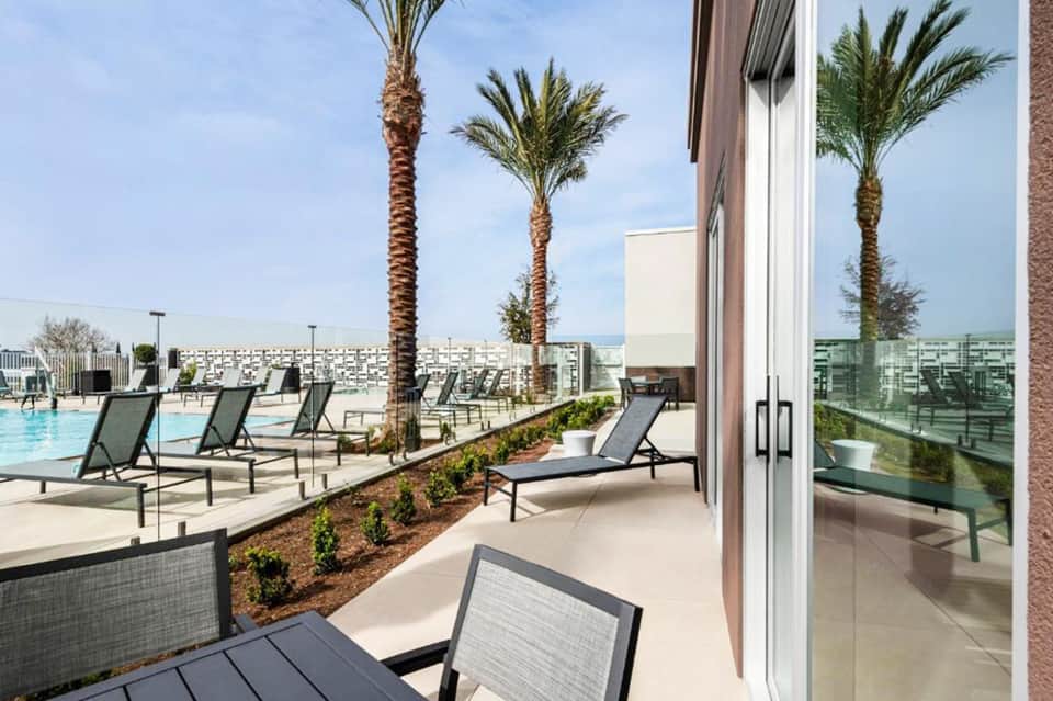 Rooftop pool deck with loungers, palm trees, and city skyline views on clear day