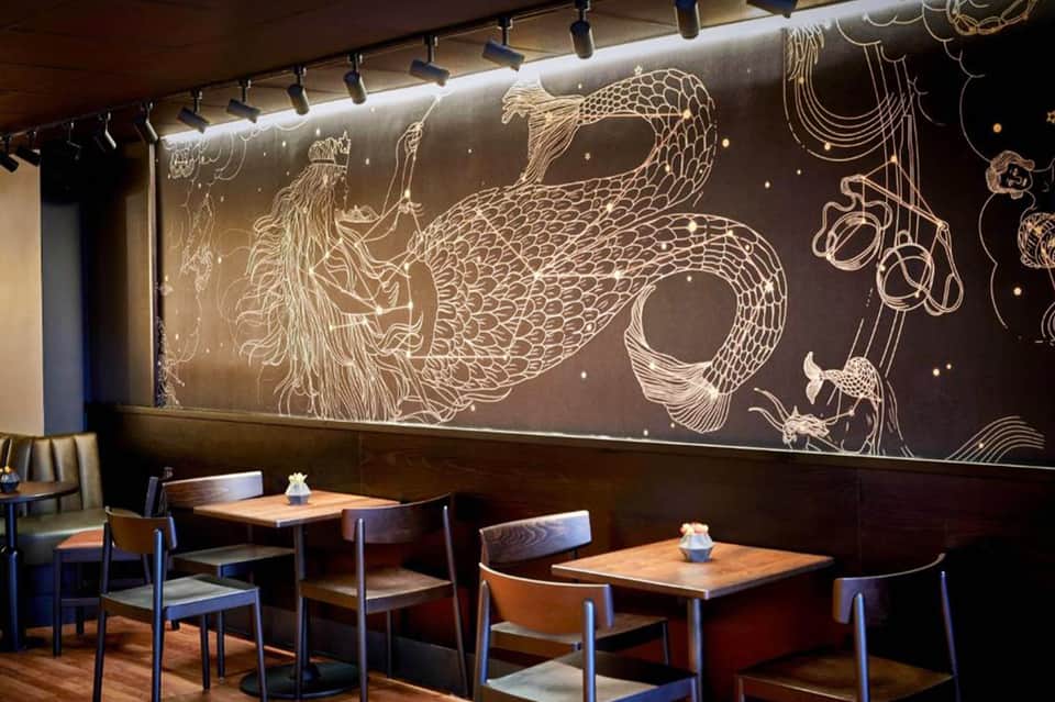 Modern restaurant dining area with dark walls and ornate golden dragon mural artwork