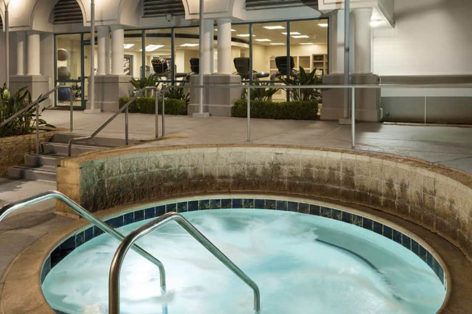 Indoor spa facility with circular hot tub, arched architecture, glass walls, and modern office space