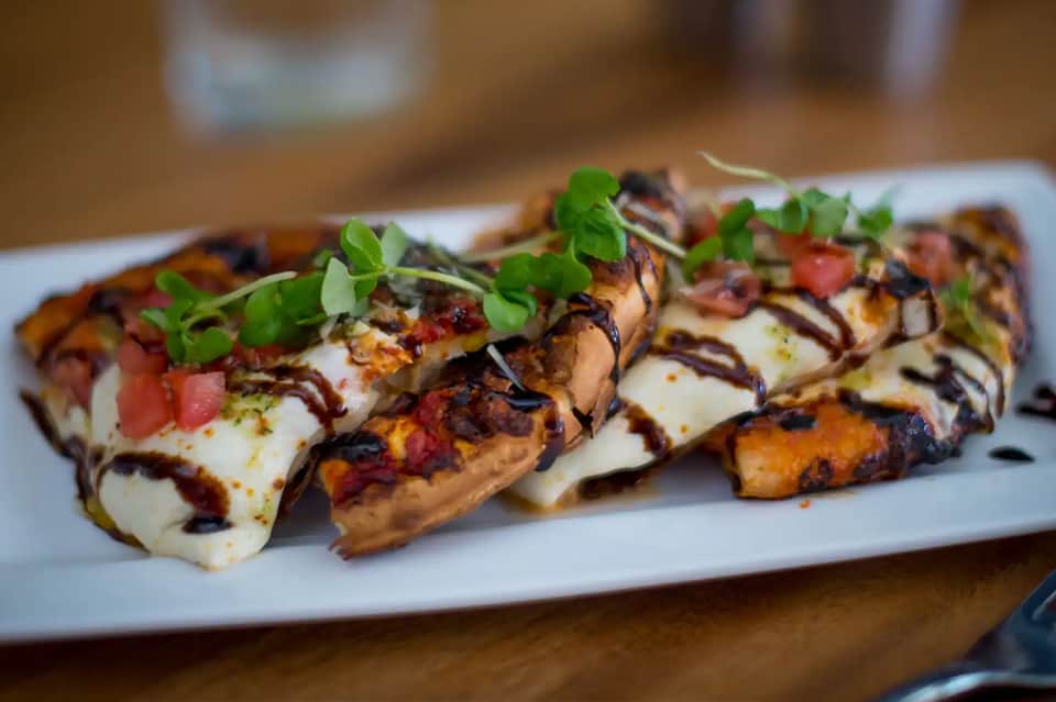 Gourmet appetizer plate with charred bread, cheese, and fresh microgreens garnish