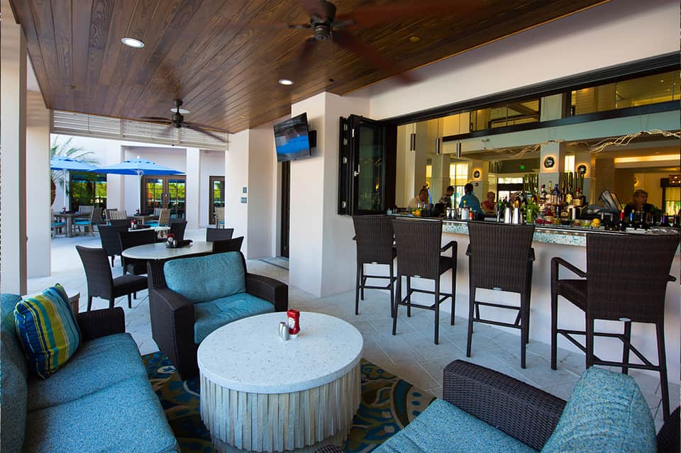 Modern hotel bar and lounge with blue seating, white marble table, dark wood ceiling, and open concept design