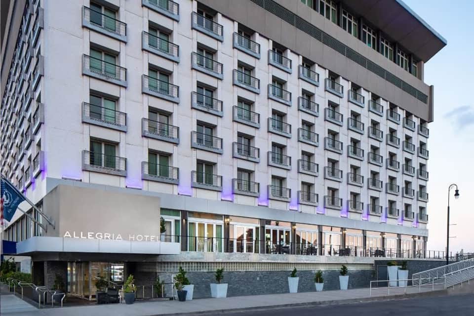 Modern Allegria Hotel building exterior with white facade and purple accent lighting at night
