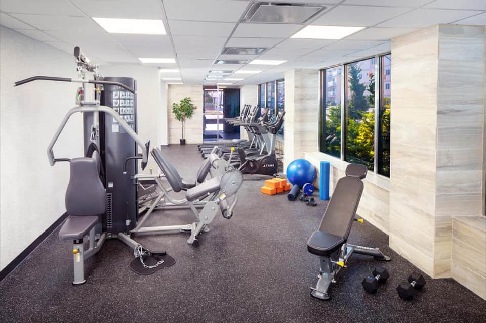 Fitness center with cardio equipment, free weights, exercise ball, and large windows